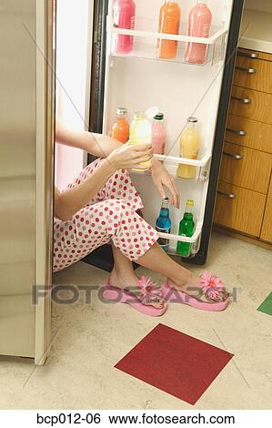 Stock Photograph - Young woman's arms and legs sticking out of a refrigerator.. Fotosearch