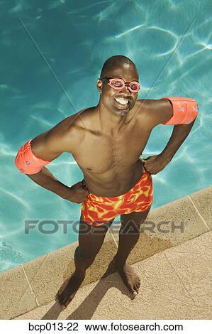 Stock Image - A man with his hands on hips at poolside. . Fotosearch