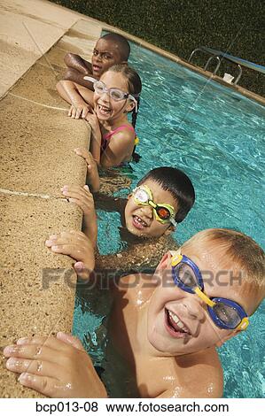 Stock Photo - Four young swimmers on the edge of a pool.. Fotosearch
