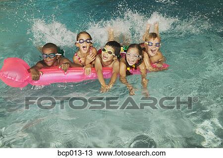 Stock Image - Group of kids in goggles on a pink float in a pool.. Fotosearch