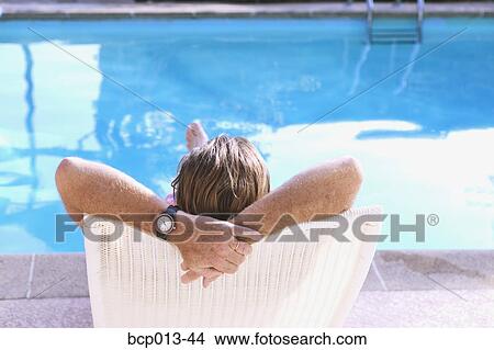 Rear view of a man relaxing in a poolside lounge chair. View Large Photo Image Picture - Rear view of a man relaxing in a poolside lounge chair.. Fotosearch