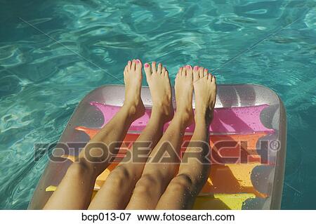 Stock Photo - Two pairs of girls' legs on a raft.. Fotosearch