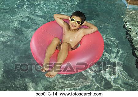 Young boy floating in a swimming pool. View Large Photo Image Picture - Young boy floating in a swimming pool.. Fotosearch