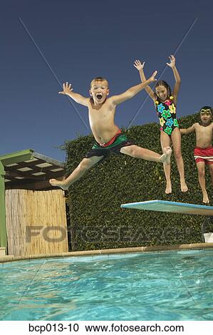 Young boy leaping off a diving board. View Large Photo Image Stock Image - Young boy leaping off a diving board.. Fotosearch