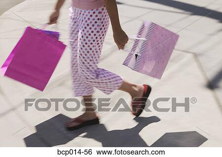 Stock Photograph - A woman in polka dot pants carrying shopping bags.. Fotosearch