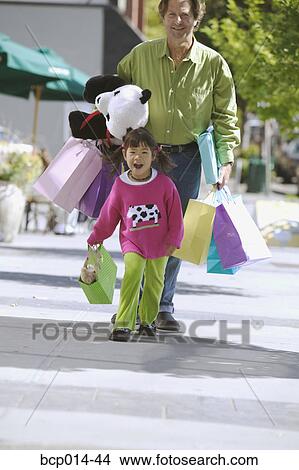 A young girl shopping with her father. View Large Photo Image Picture - A young girl shopping with her father.. Fotosearch