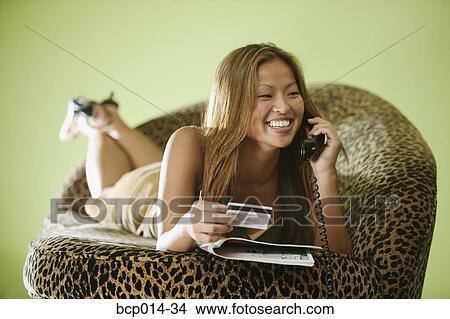 A young woman shopping with her credit card over the telephone. View Large Photo Image Picture - A young woman shopping with her credit card over the telephone. . Fotosearch