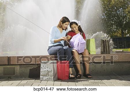 Stock Photo - Mother and daughter looking at their purchases.. Fotosearch