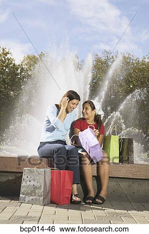 Stock Photograph - Mother and daughter looking at their purchases.. Fotosearch