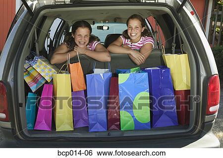 Twin teenage girls surrounded by shopping bags in a car. View Large Photo Image Stock Photograph - Twin teenage girls surrounded by shopping bags in a car. . Fotosearch