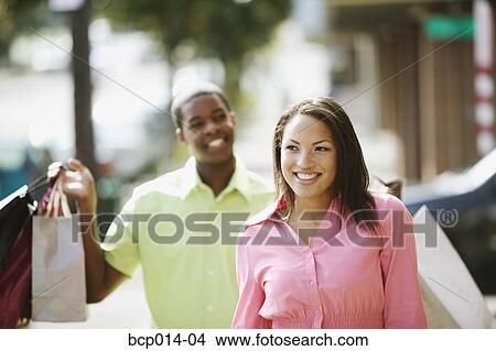 Young couple strolling and carrying shopping bags. View Large Photo Image Picture - Young couple strolling and carrying shopping bags. . Fotosearch