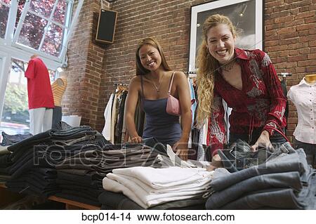 Young women looking through pants in a clothing store. View Large Photo Image Picture - Young women looking through pants in a clothing store. . Fotosearch