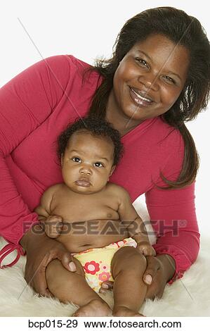 Stock Photo - A baby girl and her mom on a fur rug.. Fotosearch