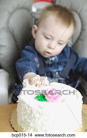 A baby girl reaching out to grab a cake. View Large Photo Image Picture - A baby girl reaching out to grab a cake.. Fotosearch