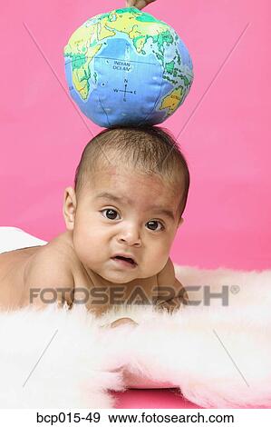 A baby girl with a soft globe balanced on her head. View Large Photo Image Stock Photo - A baby girl with a soft globe balanced on her head. . Fotosearch