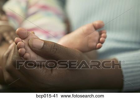 A mother holding her baby daughter's feet. View Large Photo Image Stock Image - A mother holding her baby daughter's feet. . Fotosearch