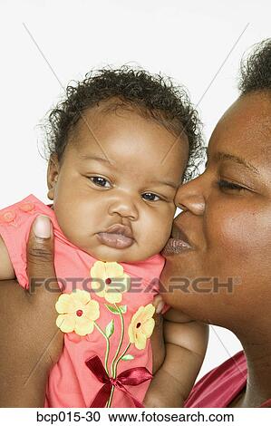 A mother kissing her baby girl on the cheek. View Large Photo Image Stock Image - A mother kissing her baby girl on the cheek. . Fotosearch