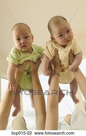 Parents holding up their twin babies. View Large Photo Image Stock Image - Parents holding up their twin babies.. Fotosearch