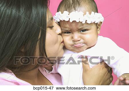 Young mother kissing her baby daughter on the cheek. View Large Photo Image Stock Photo - Young mother kissing her baby daughter on the cheek. . Fotosearch