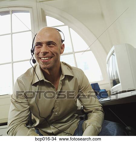 A man having a conversation on a headset telephone. View Large Photo Image Picture - A man having a conversation on a headset telephone.. Fotosearch