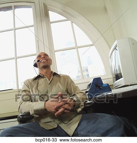 Stock Image - A man having a relaxed conversation on a headset telephone.. Fotosearch