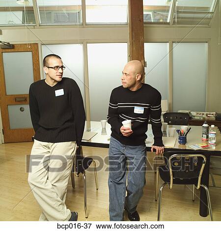 Stock Photo - Male colleagues leaning on a conference room table.. Fotosearch