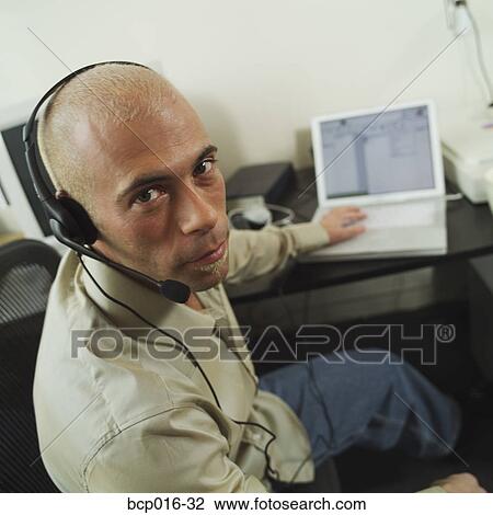 Man using a telephone headset at his desk. View Large Photo Image Stock Image - Man using a telephone headset at his desk.. Fotosearch