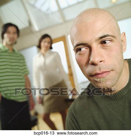 Stock Image - Man with two colleagues in the background.. Fotosearch