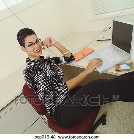 Stock Photo - Woman working on a computer at her desk.. Fotosearch