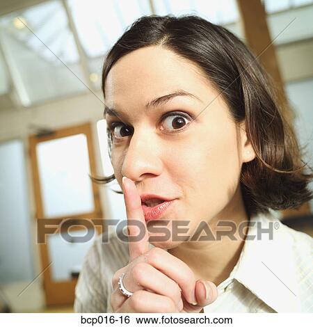 Stock Photograph - Young woman with a finger to her lips.. Fotosearch