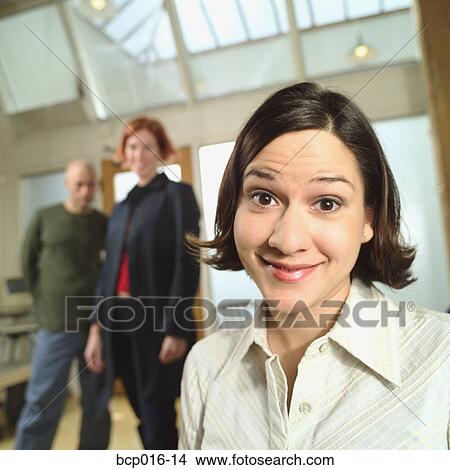 Picture - Young woman with colleagues in the background.. Fotosearch