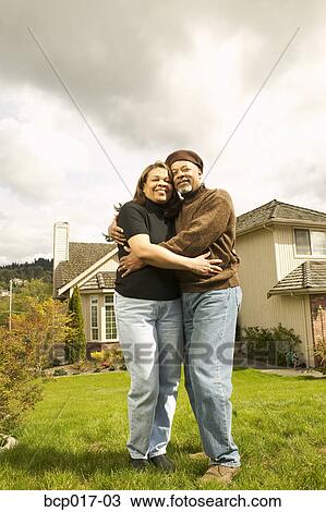 A couple hugging in front of their home. View Large Photo Image Stock Image - A couple hugging in front of their home.. Fotosearch