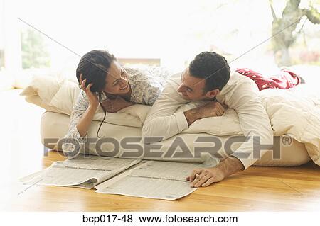 A couple lounge in bed while reading the newspaper. View Large Photo Image Stock Photo - A couple lounge in bed while reading the newspaper.. Fotosearch
