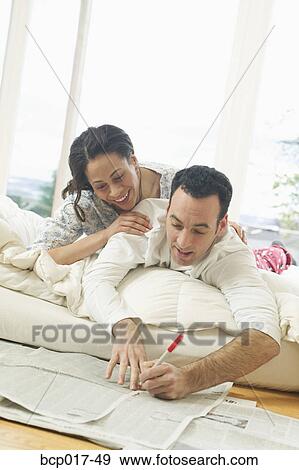 A couple lounge in bed while reading the newspaper. View Large Photo Image Stock Photo - A couple lounge in bed while reading the newspaper.. Fotosearch