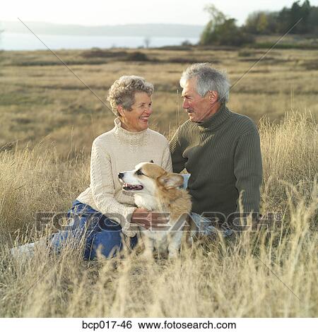 A senior couple relaxing outside with their dog. View Large Photo Image Stock Photograph - A senior couple relaxing outside with their dog.. Fotosearch