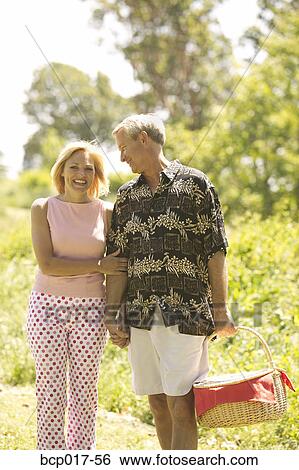 Couple strolling in the park with picnic basket. View Large Photo Image Stock Photograph - Couple strolling in the park with picnic basket.. Fotosearch