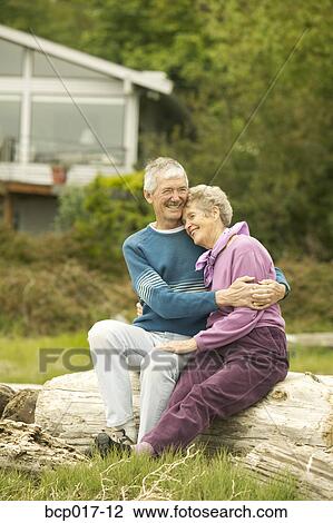 Senior couple sitting together on a log at the beach. View Large Photo Image Stock Image - Senior couple sitting together on a log at the beach.. Fotosearch