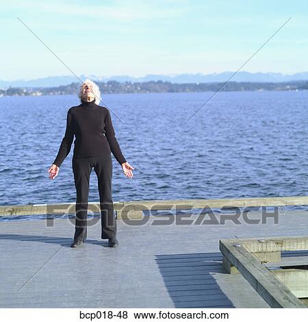 Stock Photo - An active senior woman standing on a pier.. Fotosearch