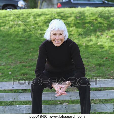 Stock Image - Portrait of a senior woman sitting on a park bench.. Fotosearch