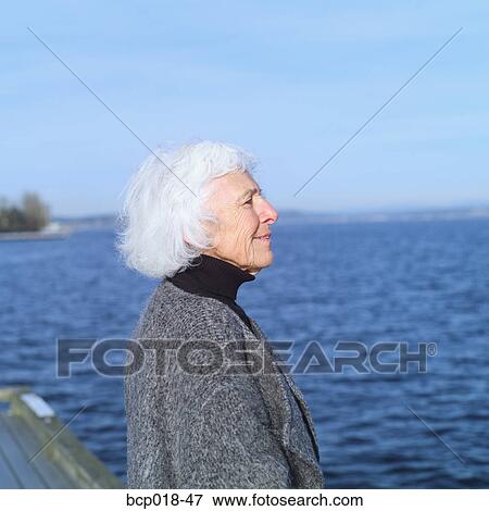 Stock Photo - Profile of a senior woman beside a lake.. Fotosearch