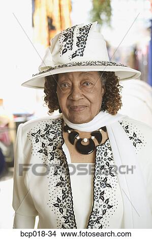 Picture - Senior woman in white dress and matching hat.. Fotosearch