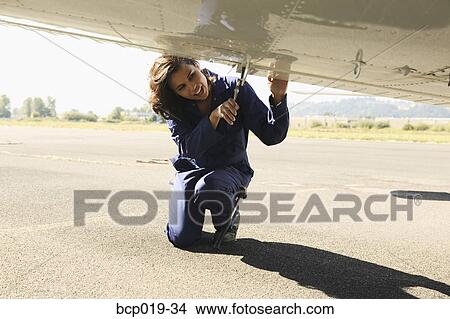 Female mechanic working on underside of airplane wing. View Large Photo Image Picture - Female mechanic working on underside of airplane wing.. Fotosearch