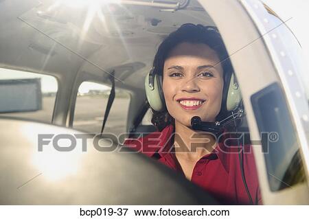 Stock Photo - Female pilot in the cockpit of an airplane. . Fotosearch