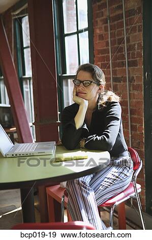 Woman sitting with laptop in a loft style office. View Large Photo Image Stock Photo - Woman sitting with laptop in a loft style office.. Fotosearch