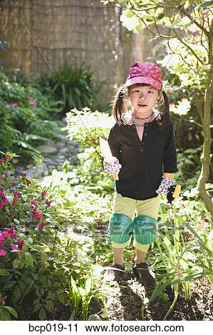 Stock Image - Young girl playing in a garden.. Fotosearch