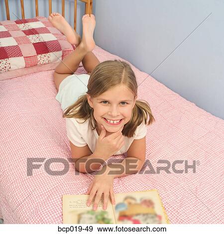 Young girl reading on her bed. View Large Photo Image Stock Photo - Young girl reading on her bed.. Fotosearch