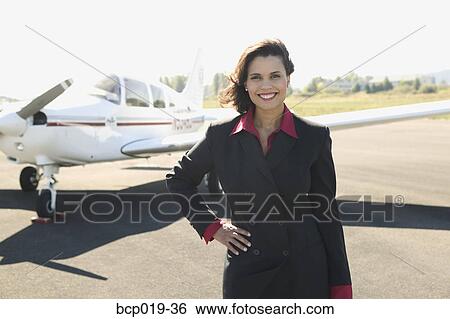 Stock Photograph - Young woman standing in front of her airplane.. Fotosearch