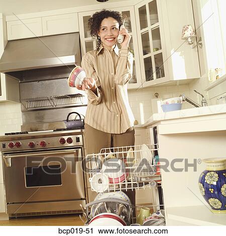 Young woman talking on the phone while loading her dishwasher. View Large Photo Image Stock Image - Young woman talking on the phone while loading her dishwasher.. Fotosearch