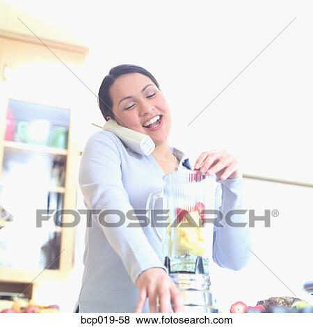 Young woman talking on the telephone while blending fruit. View Large Photo Image Stock Photo - Young woman talking on the telephone while blending fruit.. Fotosearch