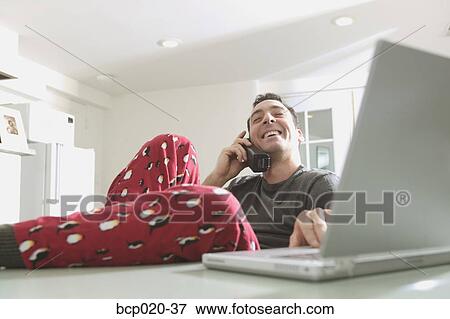 Man in pajamas talking and working on a laptop. View Large Photo Image Stock Photo - Man in pajamas talking and working on a laptop.. Fotosearch